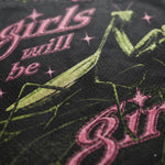 Close-up of a black mesh fabric featuring a green praying mantis graphic and pink gothic-style text reading 'girls will be'.