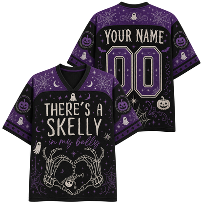 A black and purple Halloween-themed V-neck t-shirt shown from both the front and back. The front features the text 'THERE'S A SKELLY in my belly' with skeleton hands forming a heart, while the back displays 'YOUR NAME' and '00' for personalization.