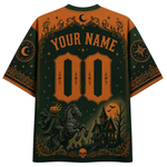 A Halloween-themed short-sleeve t-shirt shown from the back, featuring a dark green and orange color scheme with a customizable name and number print, a pumpkin horse, a haunted house, and a full moon.