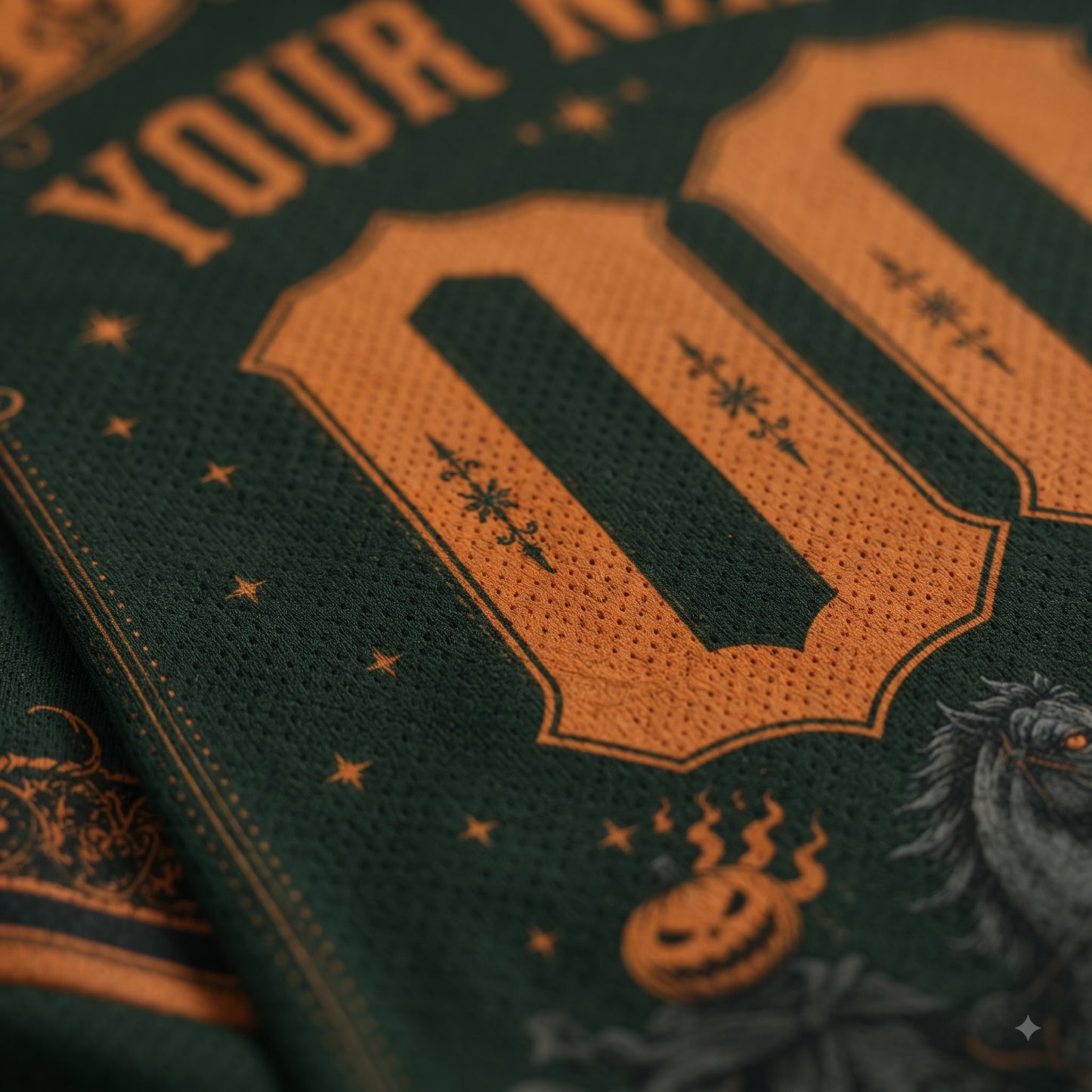 Close-up of a dark green mesh fabric with a large orange number 00, decorative stars, partial text reading 'YOUR A', and a Halloween-themed graphic near the bottom.