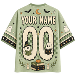 A sage green short-sleeve t-shirt with a Halloween-themed graphic design on the back, featuring 'YOUR NAME 00' for personalization, cartoon ghosts reading books, bats, stars, and a crescent moon.