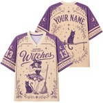 A custom short-sleeve V-neck jersey shirt shown from both front and back. The design features a purple witch illustration with a broom, cat, and stars on a beige background, with purple text reading 'SUPPORT YOUR LOCAL Witches' and 'YOUR NAME' on the back.