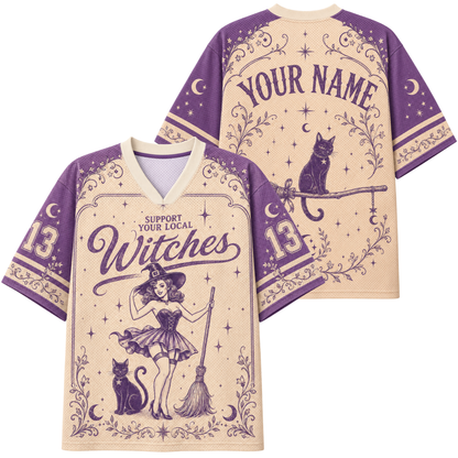A custom short-sleeve V-neck jersey shirt shown from both front and back. The design features a purple witch illustration with a broom, cat, and stars on a beige background, with purple text reading 'SUPPORT YOUR LOCAL Witches' and 'YOUR NAME' on the back.