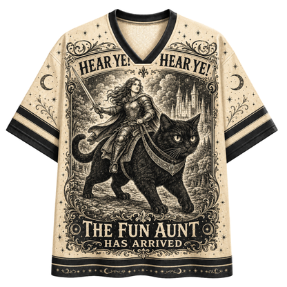 A cream-colored short-sleeve V-neck t-shirt with black trim, featuring a detailed black-and-cream graphic print of a woman riding a black cat with the text 'HEAR YE! HEAR YE! THE FUN AUNT HAS ARRIVED'.