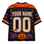 A Halloween-themed short-sleeve t-shirt with a black body, orange shoulders, and purple and orange accents. The back of the shirt features a customizable design with 'YOUR NAME' and '00' in a textured beige font, surrounded by pumpkins, bats, and stars.