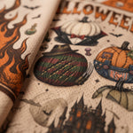 Close-up of a printed fabric featuring Halloween-themed illustrations, including pumpkins, flames, bats, a haunted castle, and the word 'Halloween' on a textured cream background.