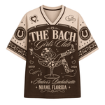 A short-sleeve V-neck t-shirt with a brown and beige graphic design. The design features the text 'THE BACH Girls Club' and 'Amber's Bachelorette Miami, Florida' with a central illustration of a woman in a martini glass.