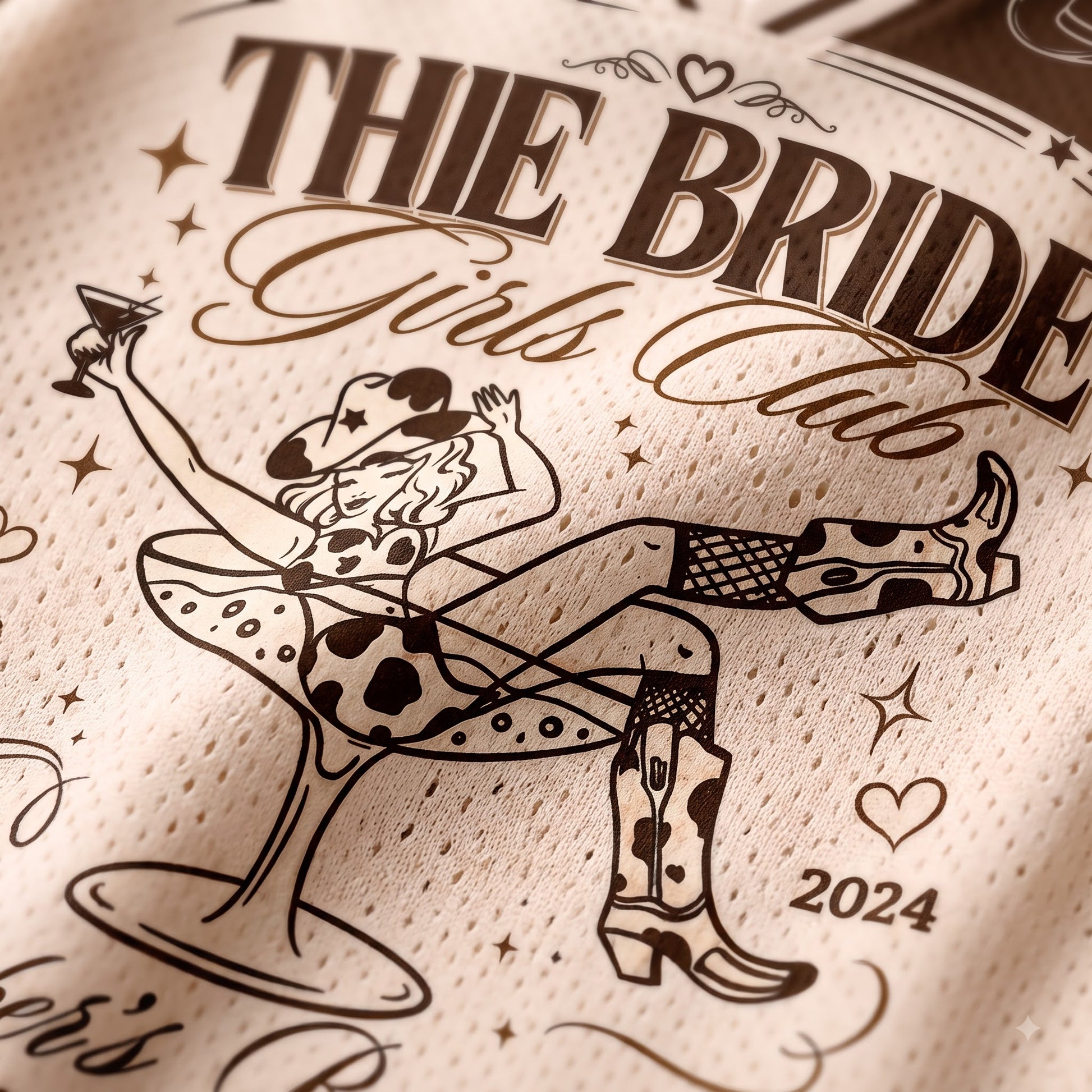 Close-up of a cream-colored mesh fabric printed with a cowgirl-themed graphic and the text 'THIE BRIDE Girls Club 2024' in dark brown.