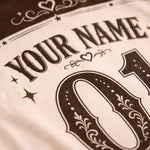 Close-up of a custom sports jersey featuring a cream-colored mesh fabric with dark brown printed text reading 'YOUR NAME' and a large decorative number '01'.