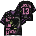 Black V-neck short-sleeve jersey-style shirt shown from front and back with a Halloween witch graphic. The front reads "girls will be girls" in pink, with a witch silhouette, bats, stars, crescent moon, and cauldron.