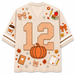 A beige mesh sports jersey with orange and white gingham details, featuring the number 12, a pumpkin, autumn leaves, bows, and school-themed illustrations on the back.