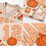 A four-panel close-up collage of a beige mesh V-neck top with orange gingham lettering and autumn-themed applique, including pumpkins, leaves, flowers, books, and a pencil.
