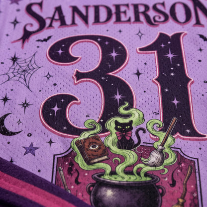 Close-up of a purple mesh fabric featuring a Halloween-themed graphic with the number 31, the word SANDERSON at the top, a black cat, green smoke, a cauldron, and stars.