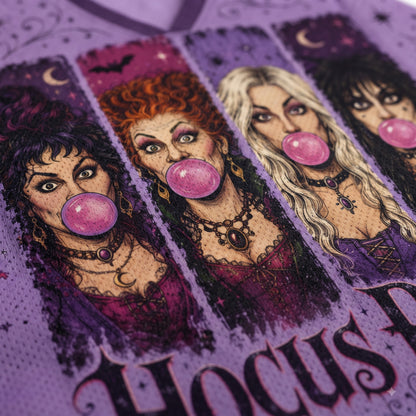 A close-up of a purple graphic print featuring four illustrated witch characters blowing pink bubblegum, with the word 'Hocus' visible at the bottom.
